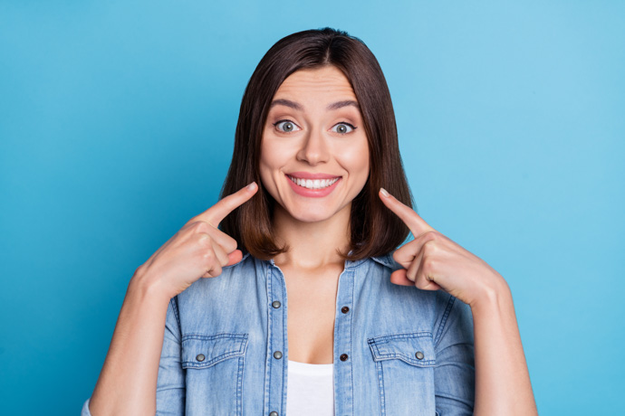 Chica enseñando dientes blanqueados en casa.