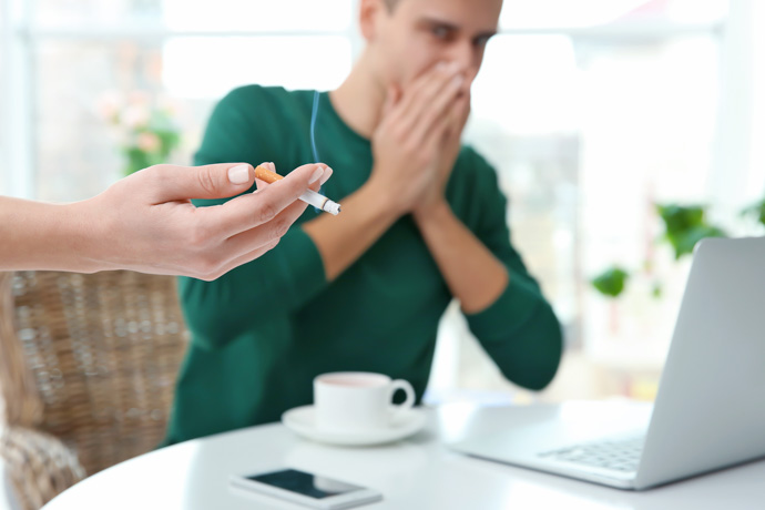 Ejemplo de fumador pasivo evitando el humo del tabaco.