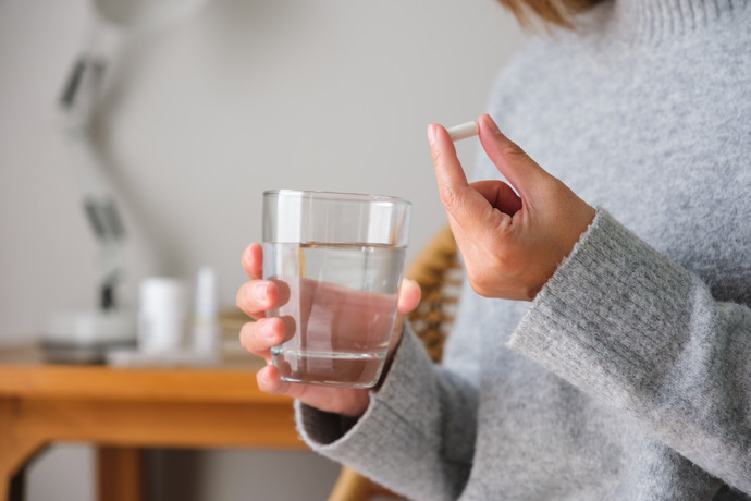 Mujer sujetando una pastilla y un vaso de agua