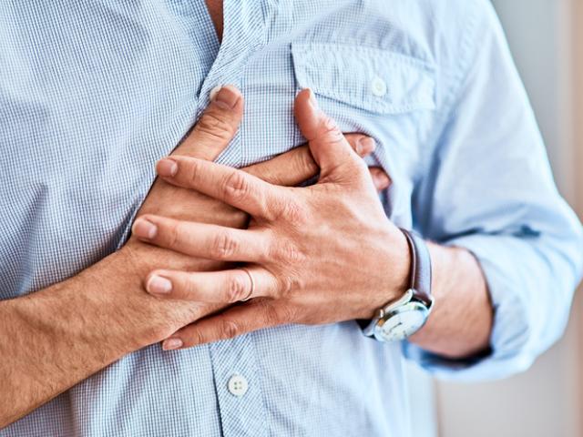 hombre sujetándose con las manos por la presión en el pecho y la falta de aire